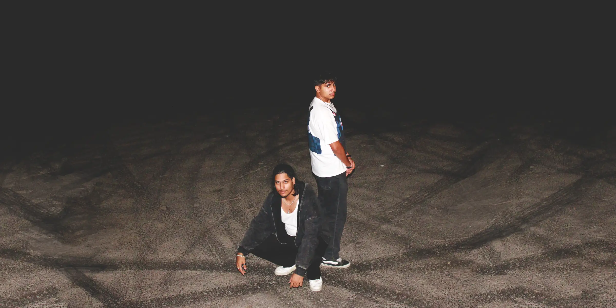 The two Moderni founders standing on asphalt at night, lit by camera flash.