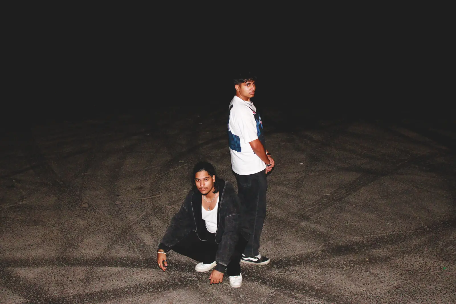 The two Moderni builders in an empty lot at night, lit by camera flash